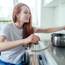 A teenage girl sitting in her wheelchair stirring a pot on the hob in the kitchen. 