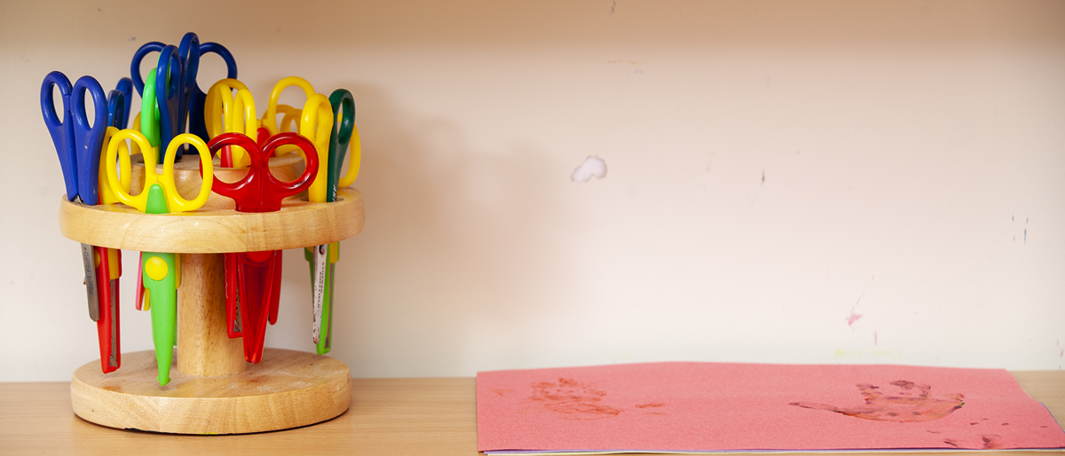 scissors in a scissor rack on a shelf with paper