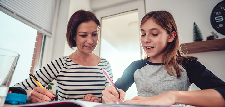 adult woman helping teenage girl with homework