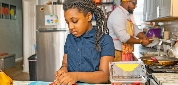 Dad and young girl preparing food in a kitchen