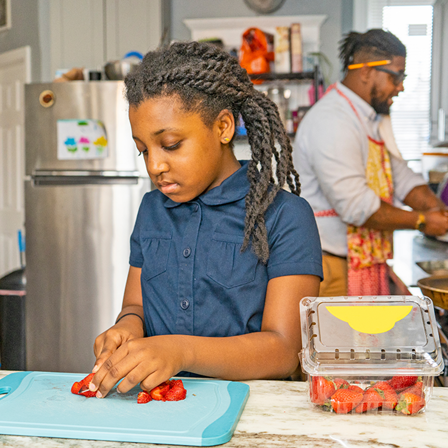 Dad and young girl preparing food in a kitchen