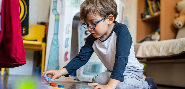 Child With Glasses Playing With Wooden Toys On Floor