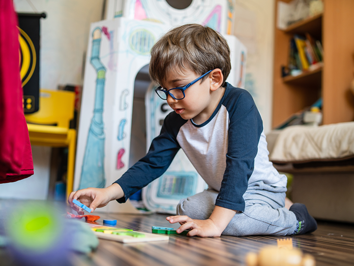 Child With Glasses Playing With Wooden Toys On Floor