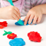 Child playing with colourful playdough on a table.