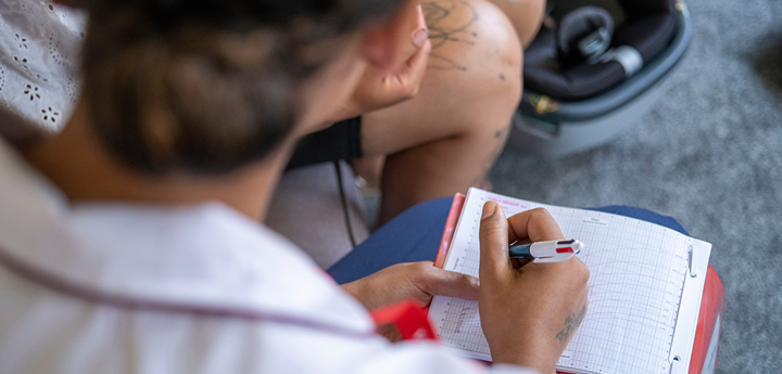 Looking over the shoulder of a woman writing on her lap in the living room.