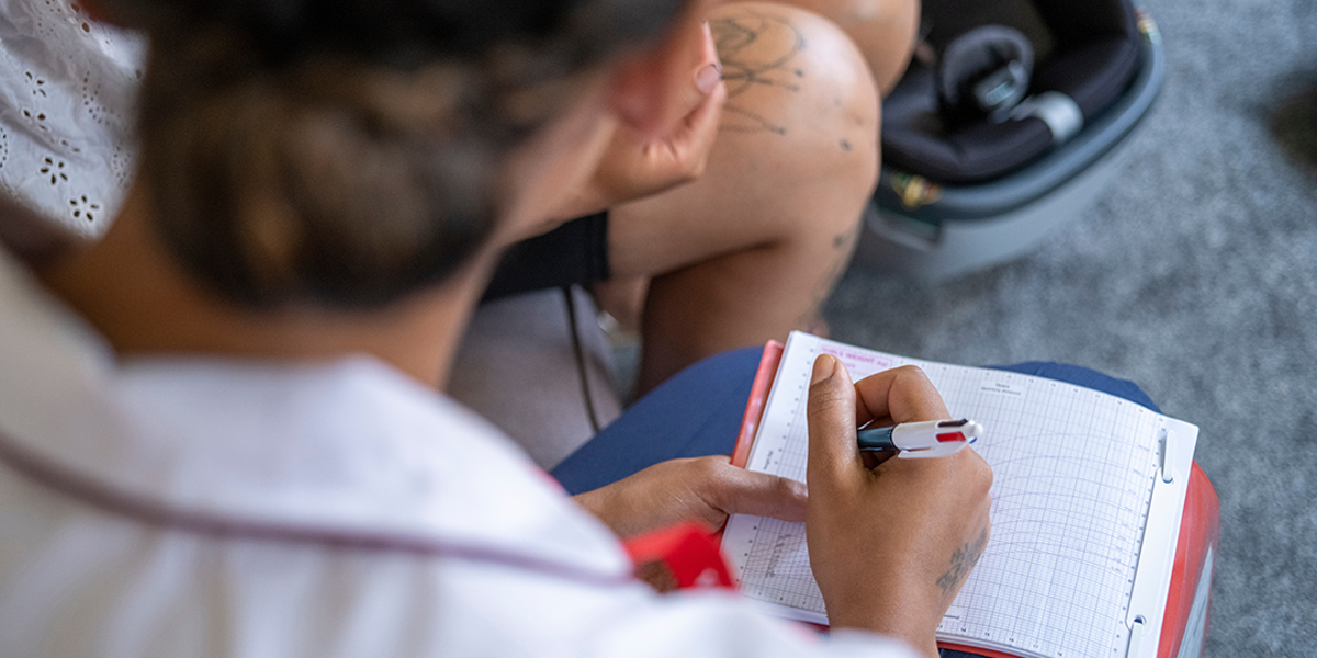 Looking over the shoulder of a woman writing on her lap in the living room.