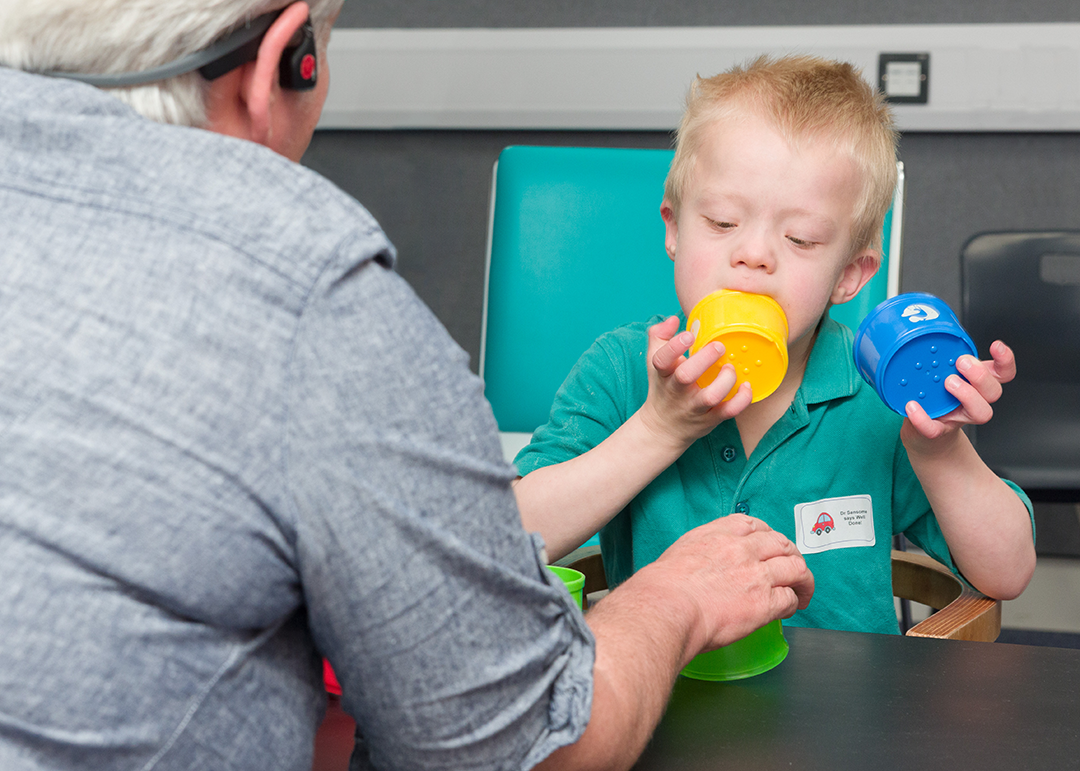 Downs syndrome child mouthing plastic cups 