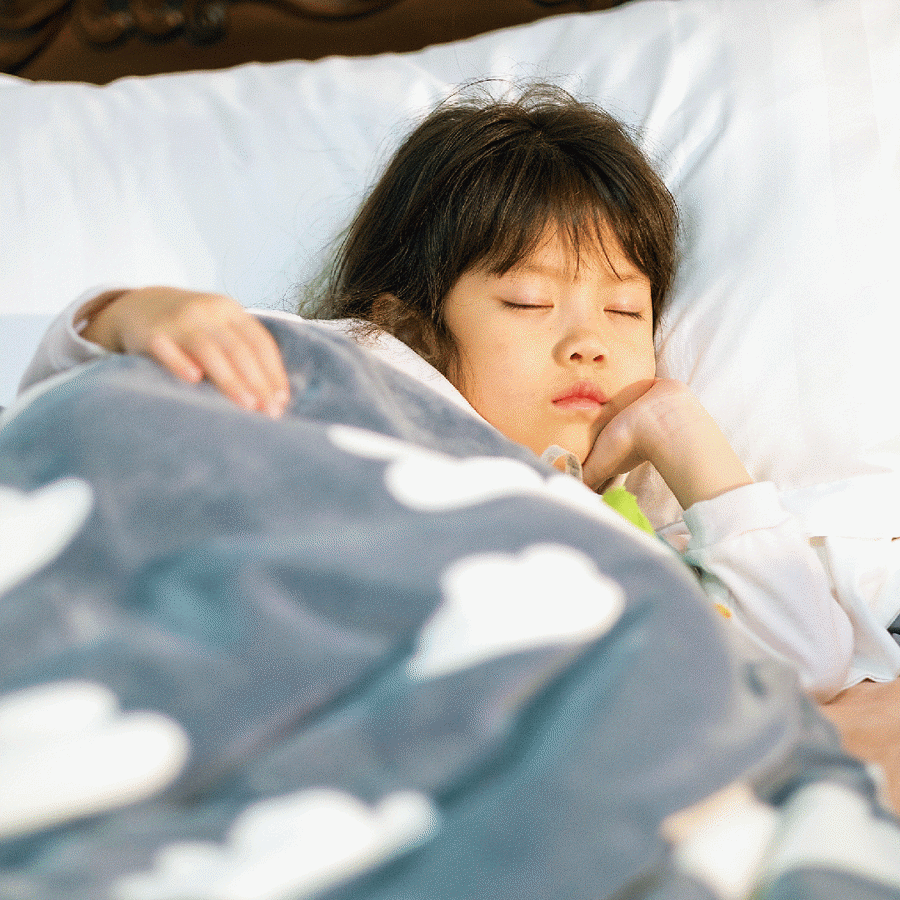 Young girl in bed with a blanket sleeping.