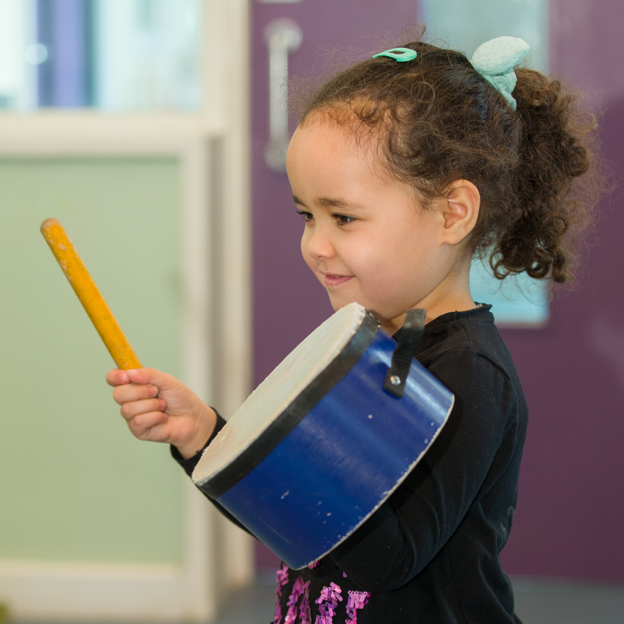 Child playing with drum and drumstick