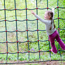 Young girl climbing on a rope net climbing frame in a woodland adventure playground. 