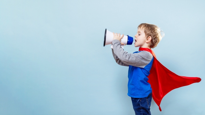 Child dressed as a superhero shouting into megaphone