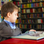 Young boy sitting at a table in a library reading a book