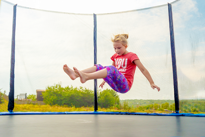 girl bouncing on trampoline outside