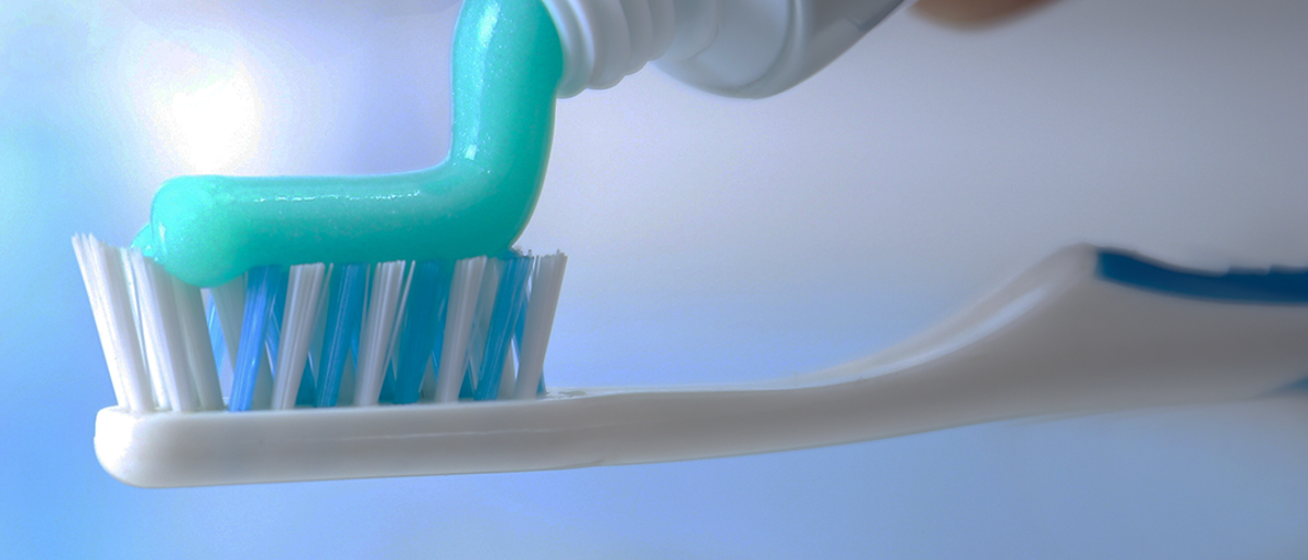 Toothpaste being squeezed onto a toothbrush.