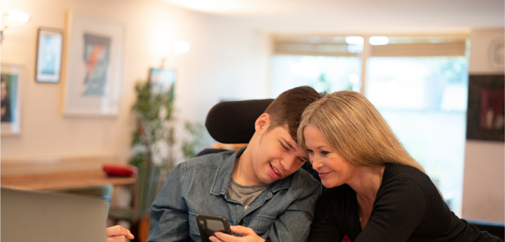 Disabled male young adult looking at phone with female adult