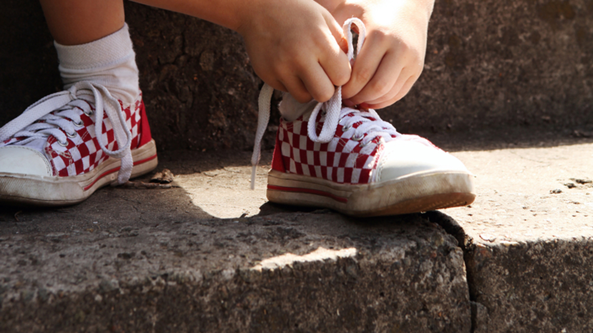 Young boy sitting on steps tying shoelace