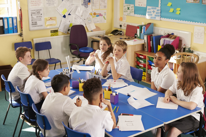 school children sitting around table talking