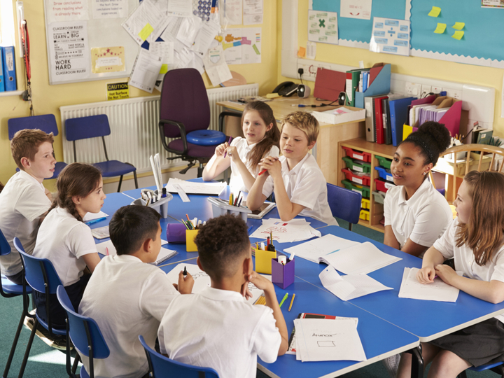 Children sitting at a table in school working on schoolwork.