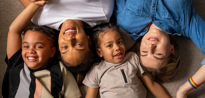 2 mums and 2 children lying on the floor smiling