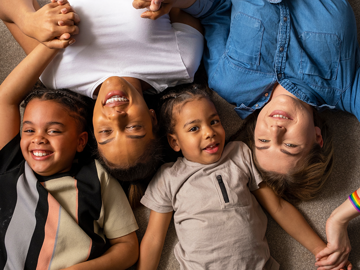 2 mums and 2 children lying on the floor smiling