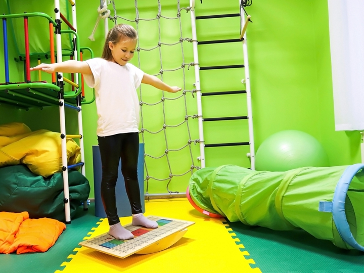 Girl standing on a balance board in a physio room.