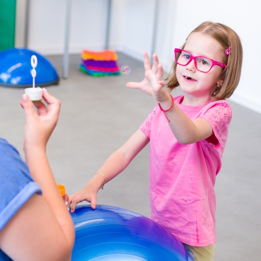 Child with cerebral palsy and adult playing with bubbles