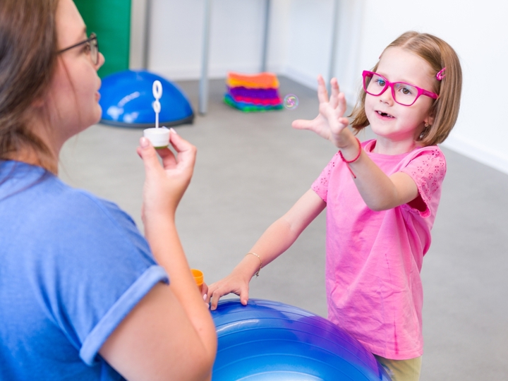 Child with cerebral palsy and adult playing with bubbles