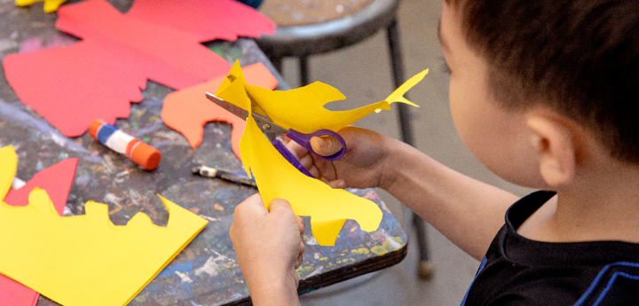 Boy cutting yellow paper using scissors