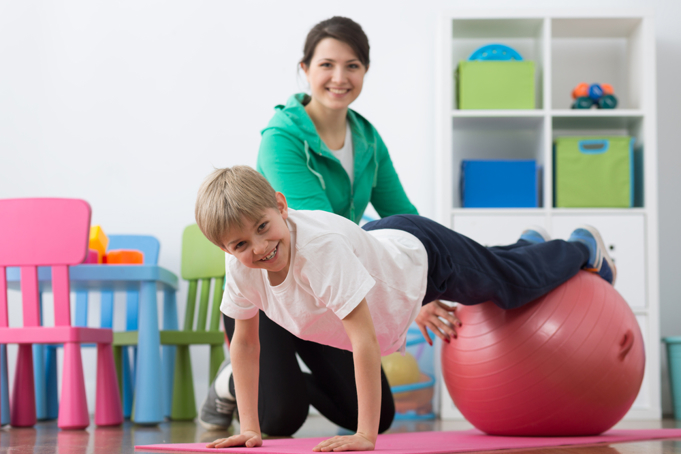 boy on hands with arms straight and feet on gym ball