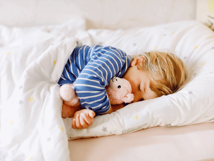 girl sleeping in bed with favourite soft plush toy llama