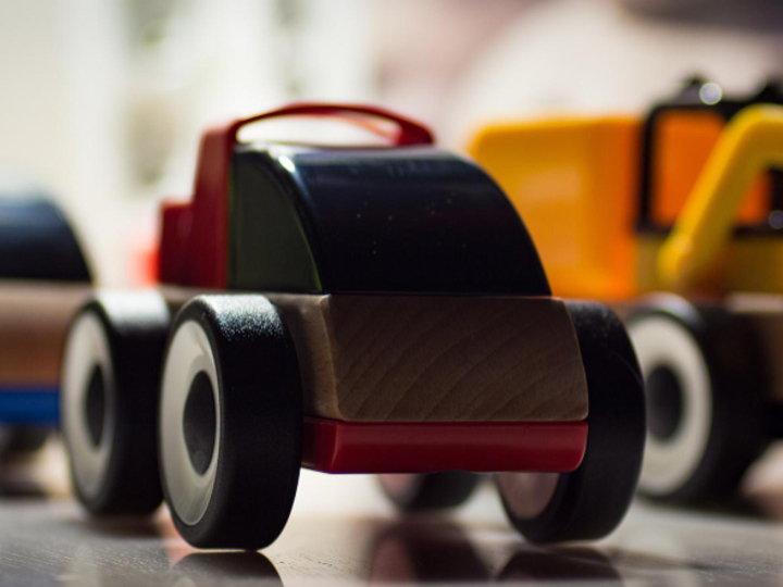 Two wooden toy cars and a yellow toy digger