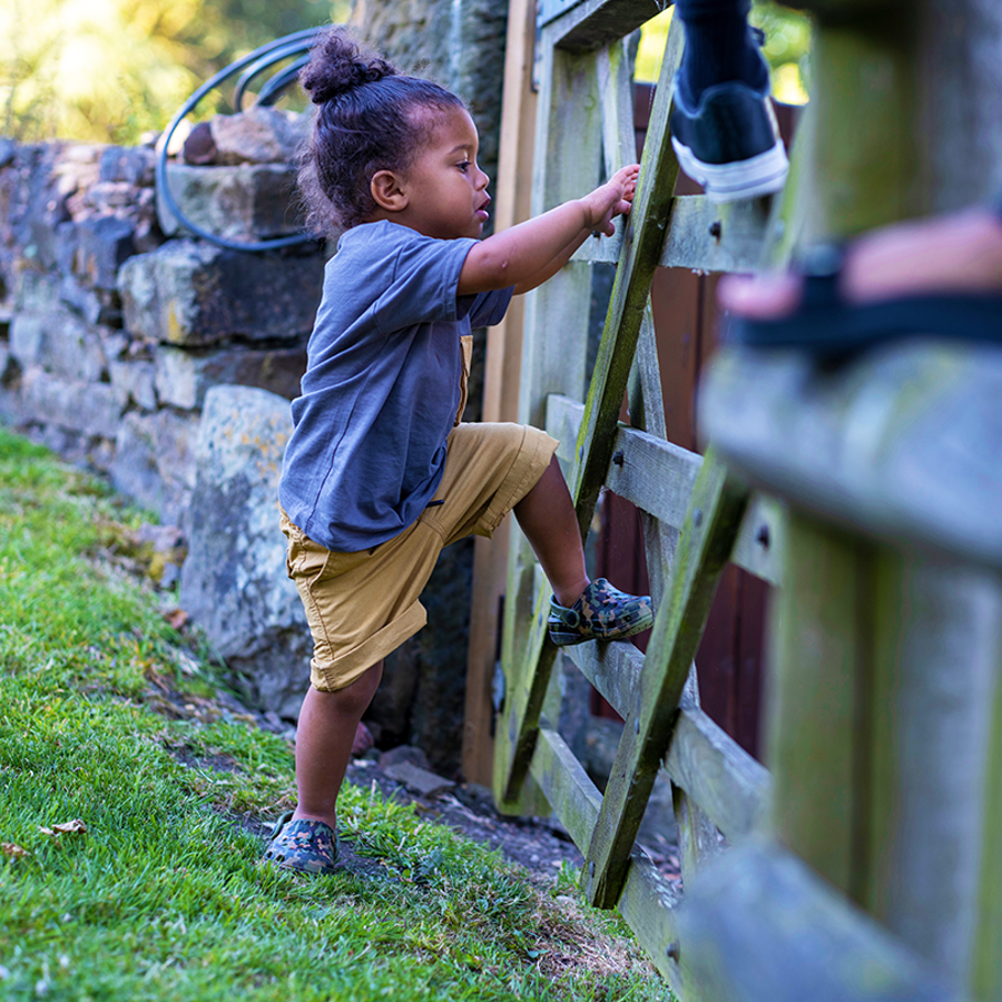 child climbing on a wooden gate during a walk outside