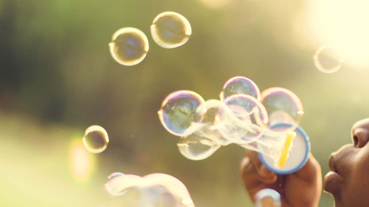 Close-up of child blowing bubbles outdoors.