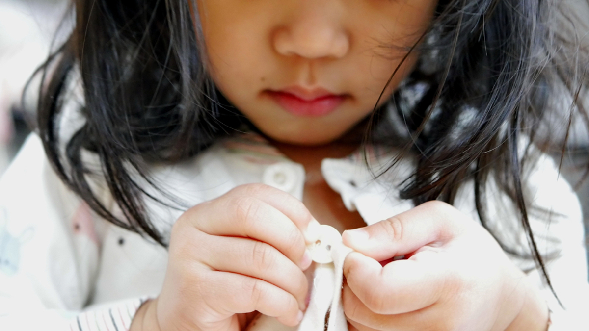 young girl buttoning up her shirt