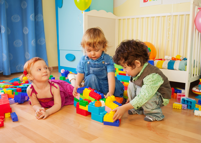 3 children playing with duplo on the floor