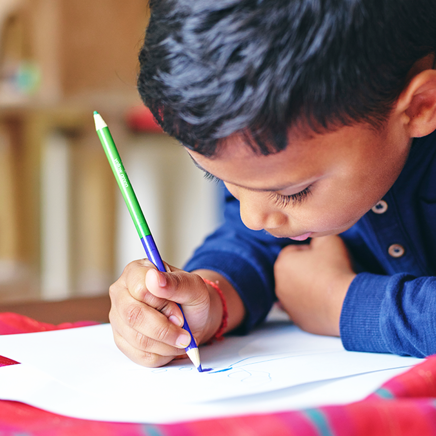 child leaning forward writing with a pencil