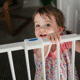 toddler smiling behind a child-gate