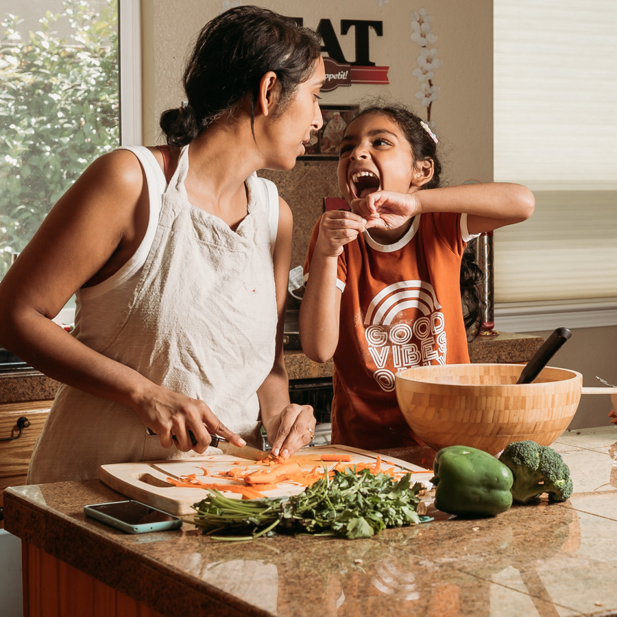 Mum and daughter preparing food while laughing together in the kitchen