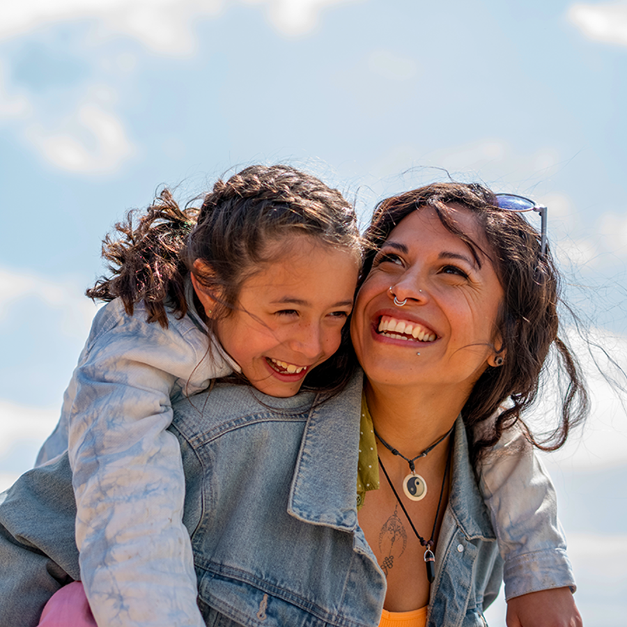 child laughing while piggybacking on an adult woman