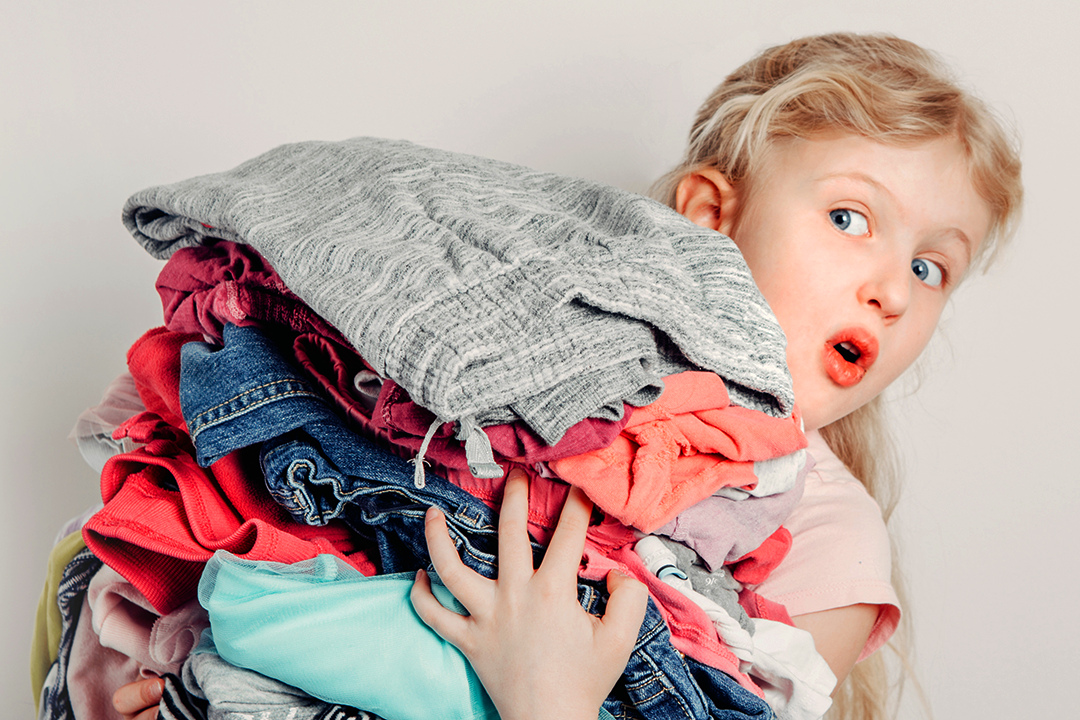 Girl holding a pile of clothes looking shocked.