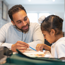 Man helping a child to learn from a book at home.