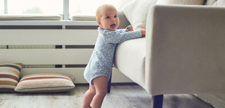 8 Month Old Baby Boy Standing Next To Sofa Holding On For Support