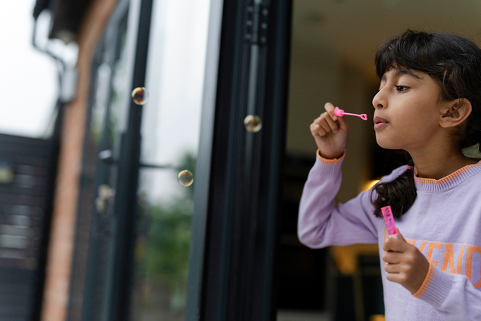 girl blowing bubbles out of door