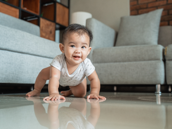 Baby crawling on floor in a living room.