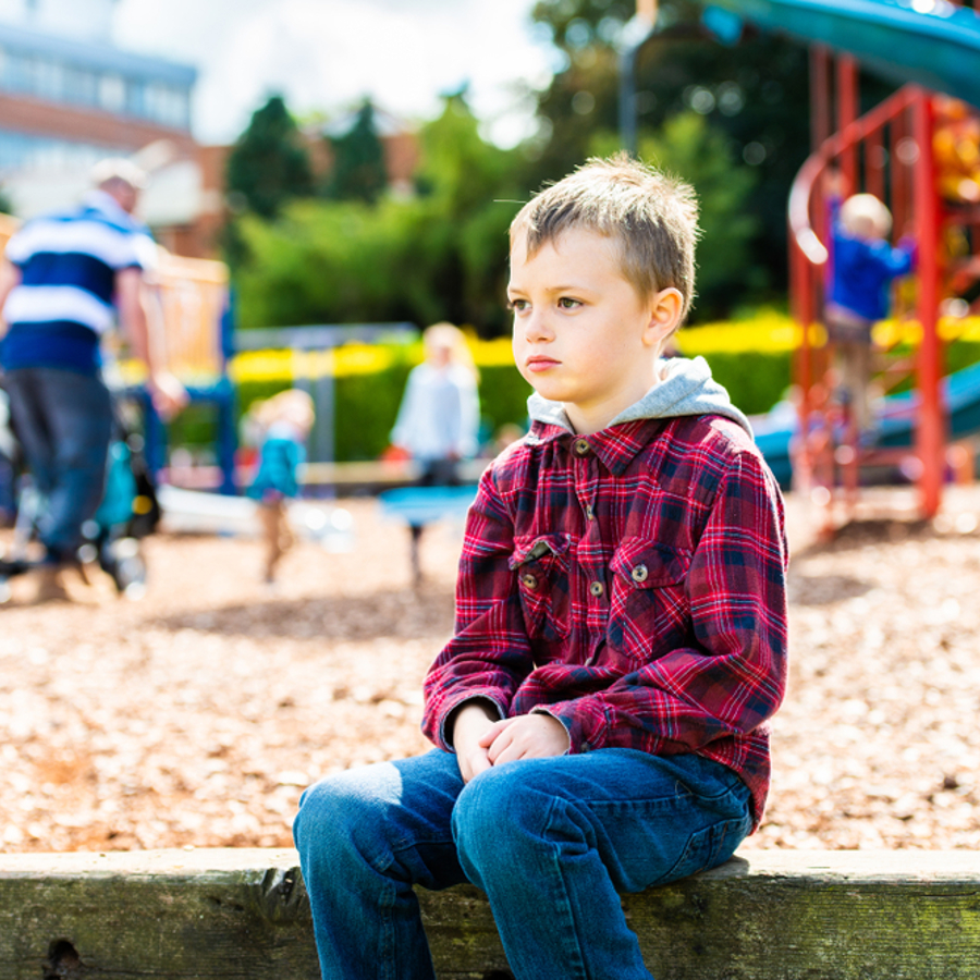 Young boy sitting on a low wall at a park