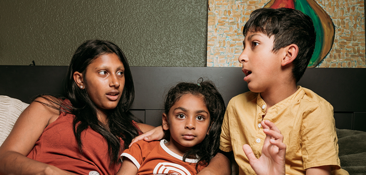 Adult and two children talking in a bed.