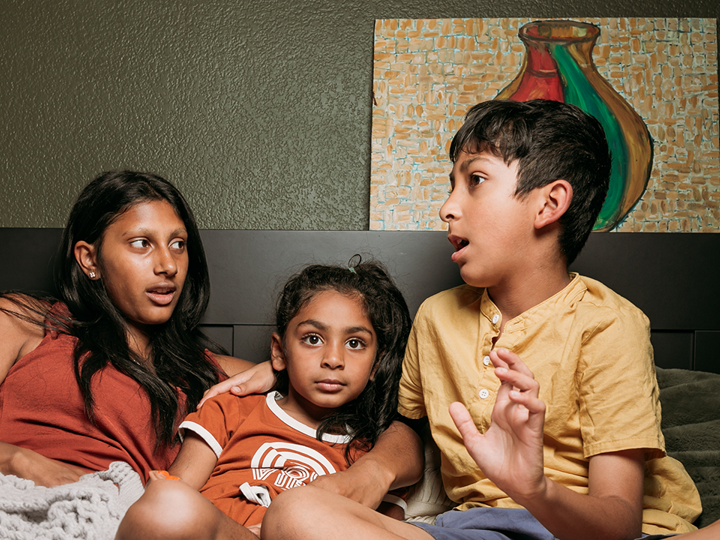 Adult and two children talking in a bed.