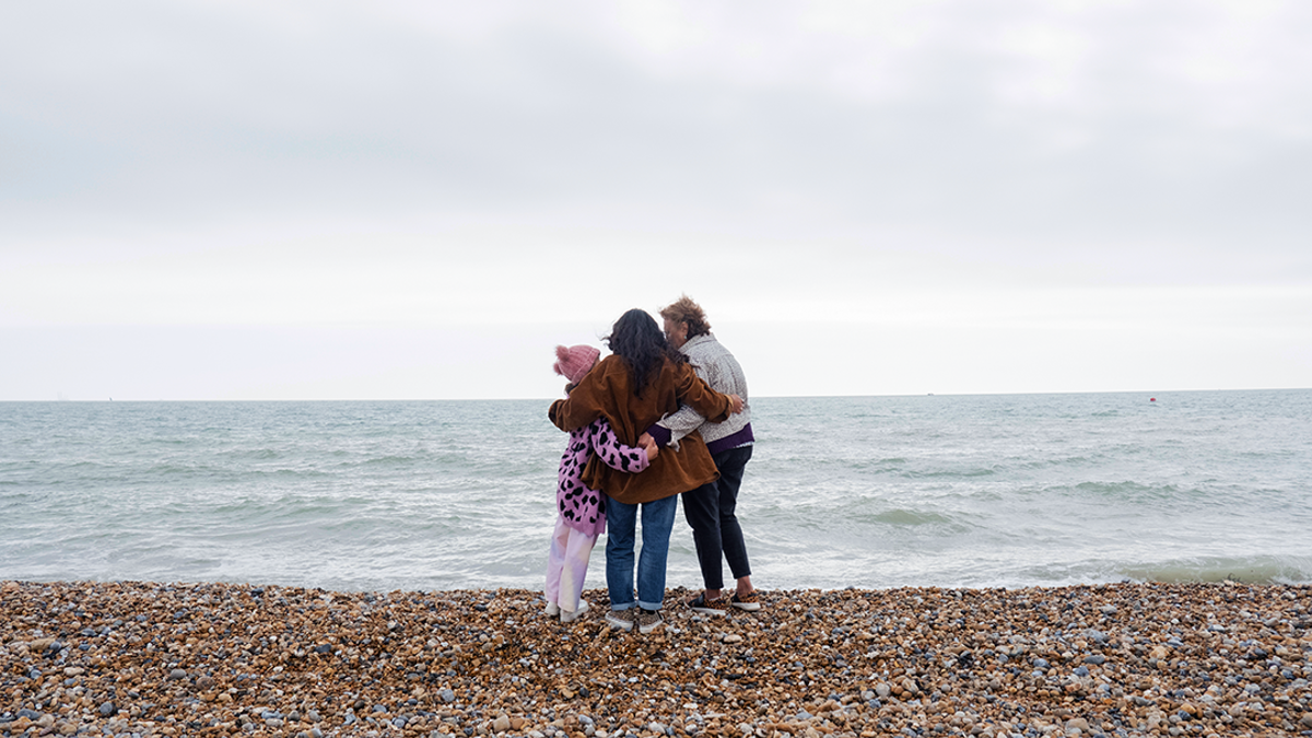 A family hugging on a pebble beach