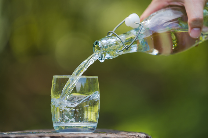 water being poured into glass tumbler from glass bottle