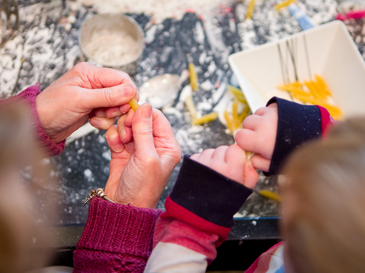Showing only their hands. Adult and child playing with food. The background is a messy table covered with flour and pasta